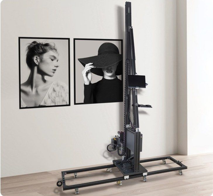 Wheel-type wall printer with slim black column on its guide-rail frame, beside two printed portraits
