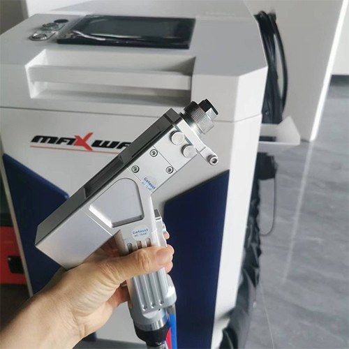 Operator holding the handheld laser welding torch in front of the MW-HW cabinet