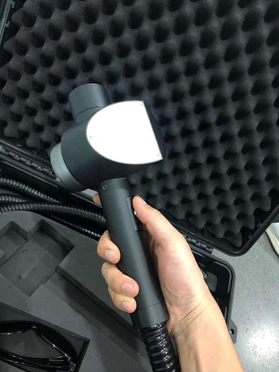 Operator holding the handheld laser cleaning head above the open transport case