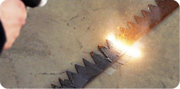 Handheld cleaning head stripping rust from a steel saw blade, with sparks at the beam line