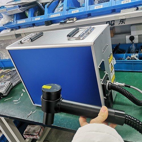 Operator holding the MW-LS50 handheld cleaning head next to the unit in the factory