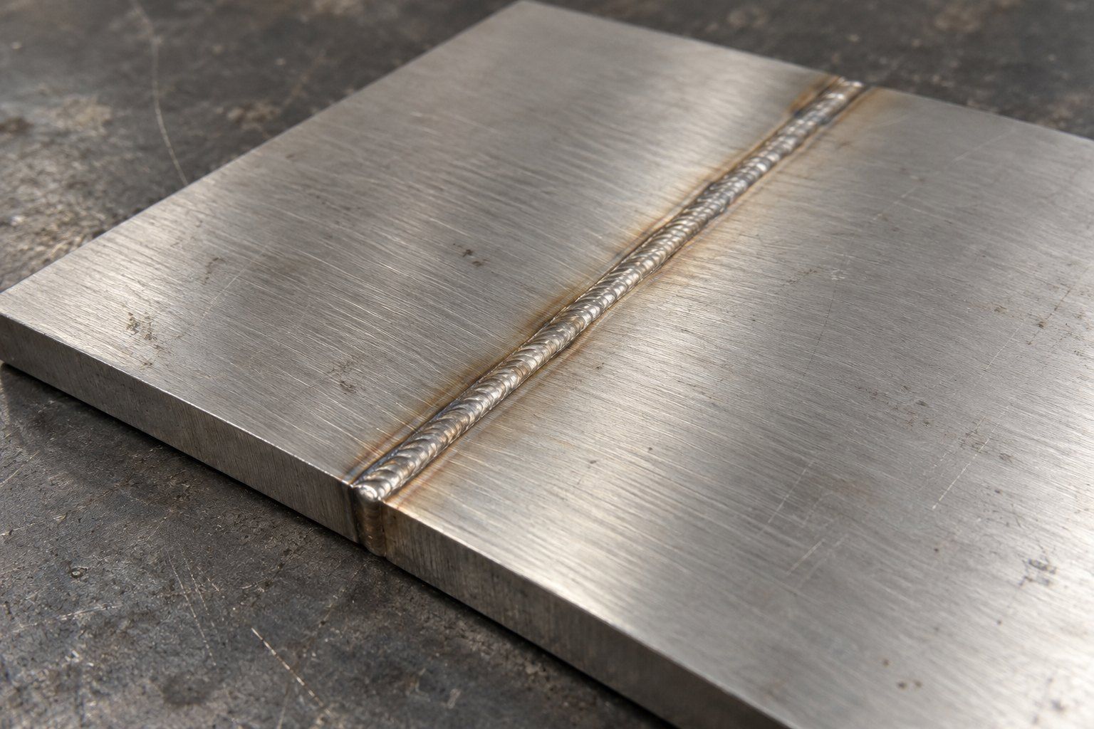 Laser weld bead along a butt joint between two thicker stainless steel plates, seen from the plate edge