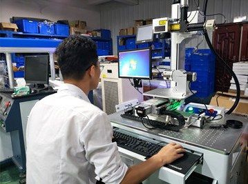 An engineer testing a fiber laser marking machine at the Maxwave workshop