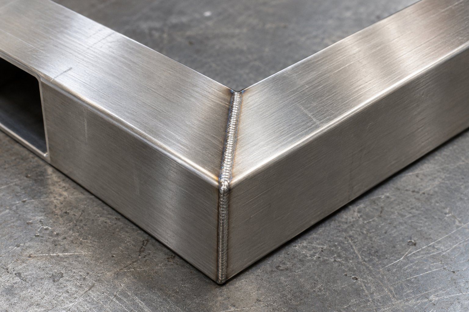 Laser-welded mitred corner of a brushed stainless steel rectangular tube frame